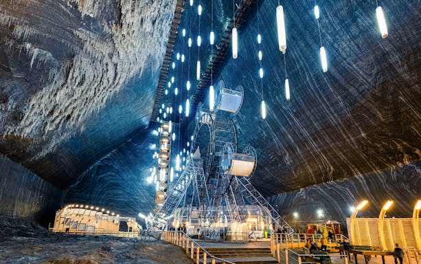 Salina Turda underground amusement park with Ferris wheel and illuminated salt walls.