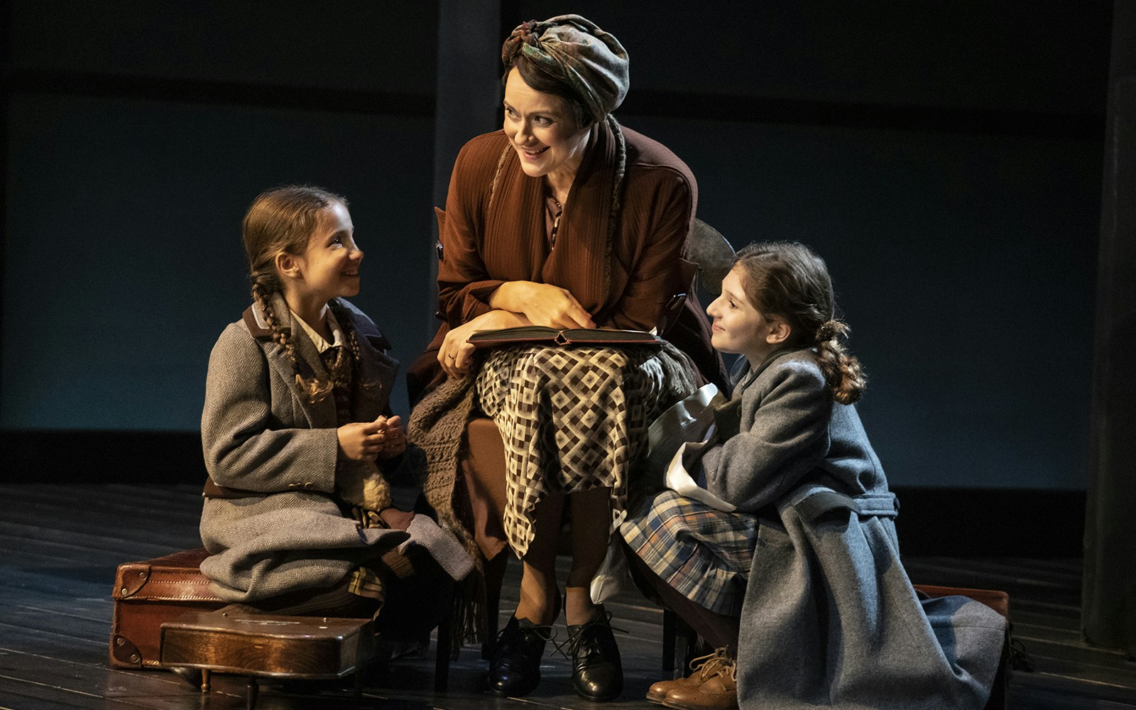 Woman reading to two children on stage in Leopoldstadt play.