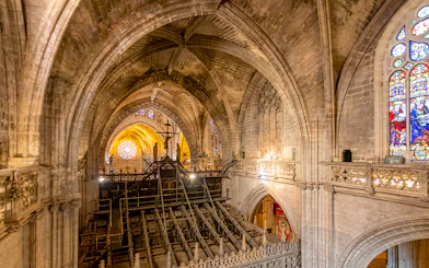 Interior view of Gothic Cathedral from balcony, showcasing vaulted ceilings and stained glass windows.