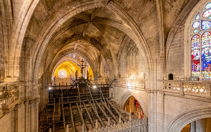 Interior view of Gothic Cathedral from balcony, showcasing vaulted ceilings and stained glass windows.