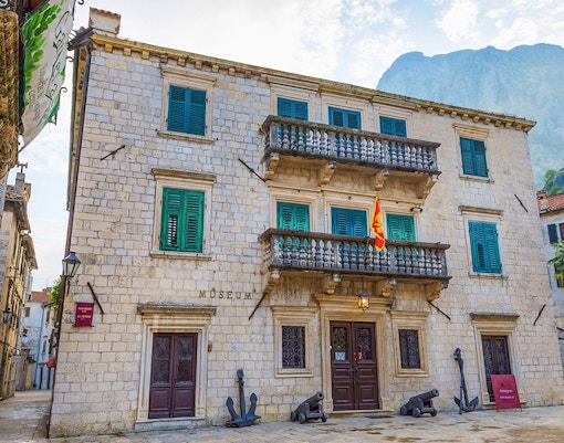Maritime museum building with flag and cannons in Kotor, Montenegro.