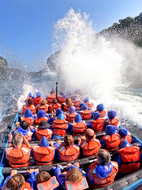 Guests on Whirlpool Jet Boat Tour in Niagara Gorge, Canada, experiencing water splashes.