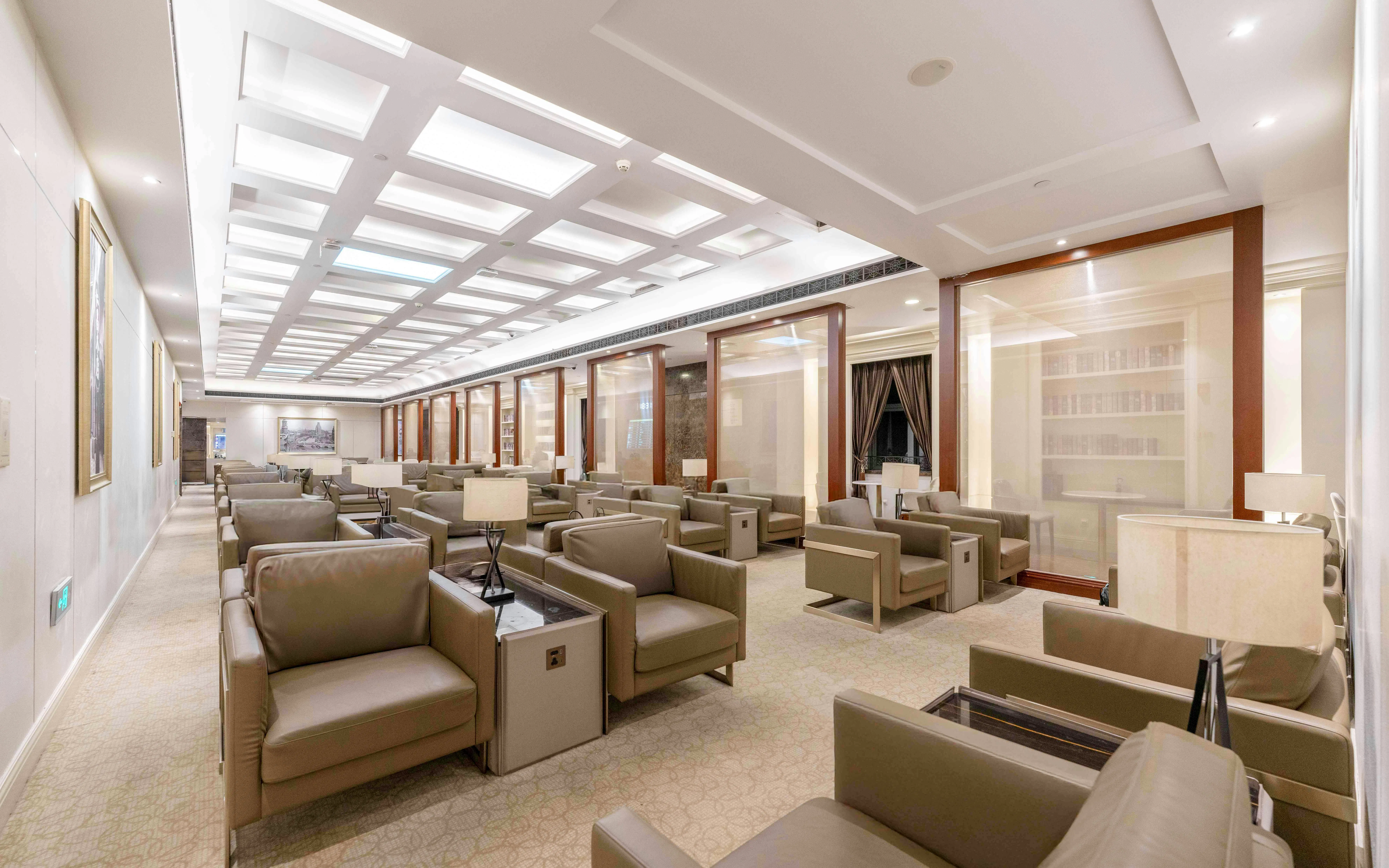 Spacious lounge area at Shanghai Pudong International Airport Terminal 1 with seating and lamps.