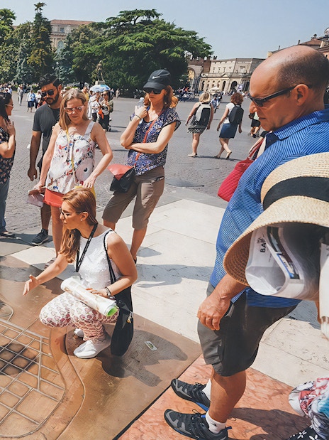 Tour guide explaining Verona Arena map to tourists outside the amphitheater.