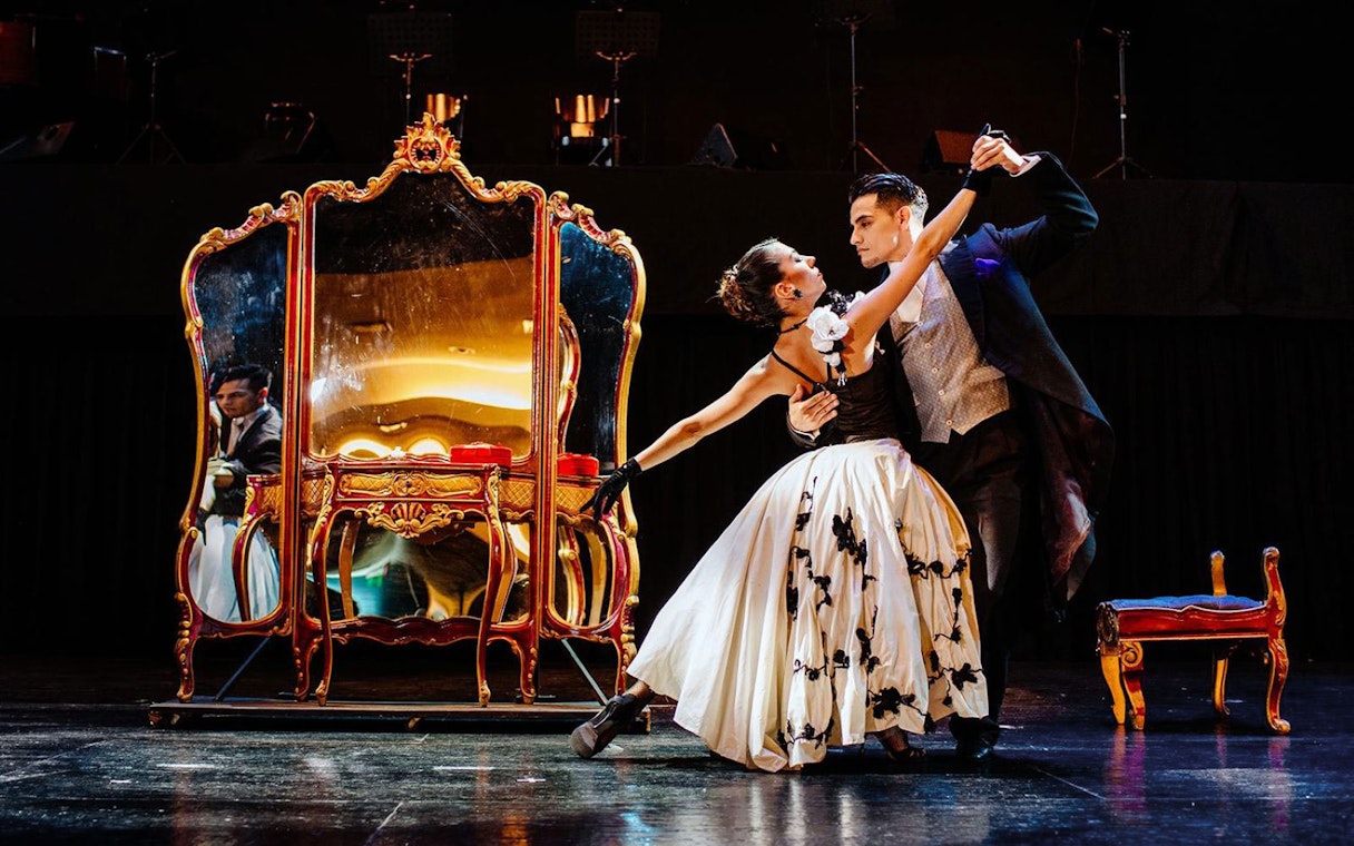 Dancers performing at Tango Porteño Show in front of ornate mirror.