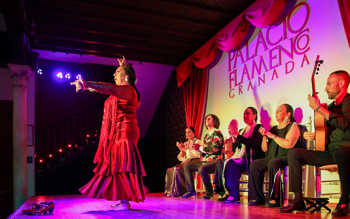 Flamenco dancer performing at Palacio de los Olvidados, Granada, with musicians and audience.