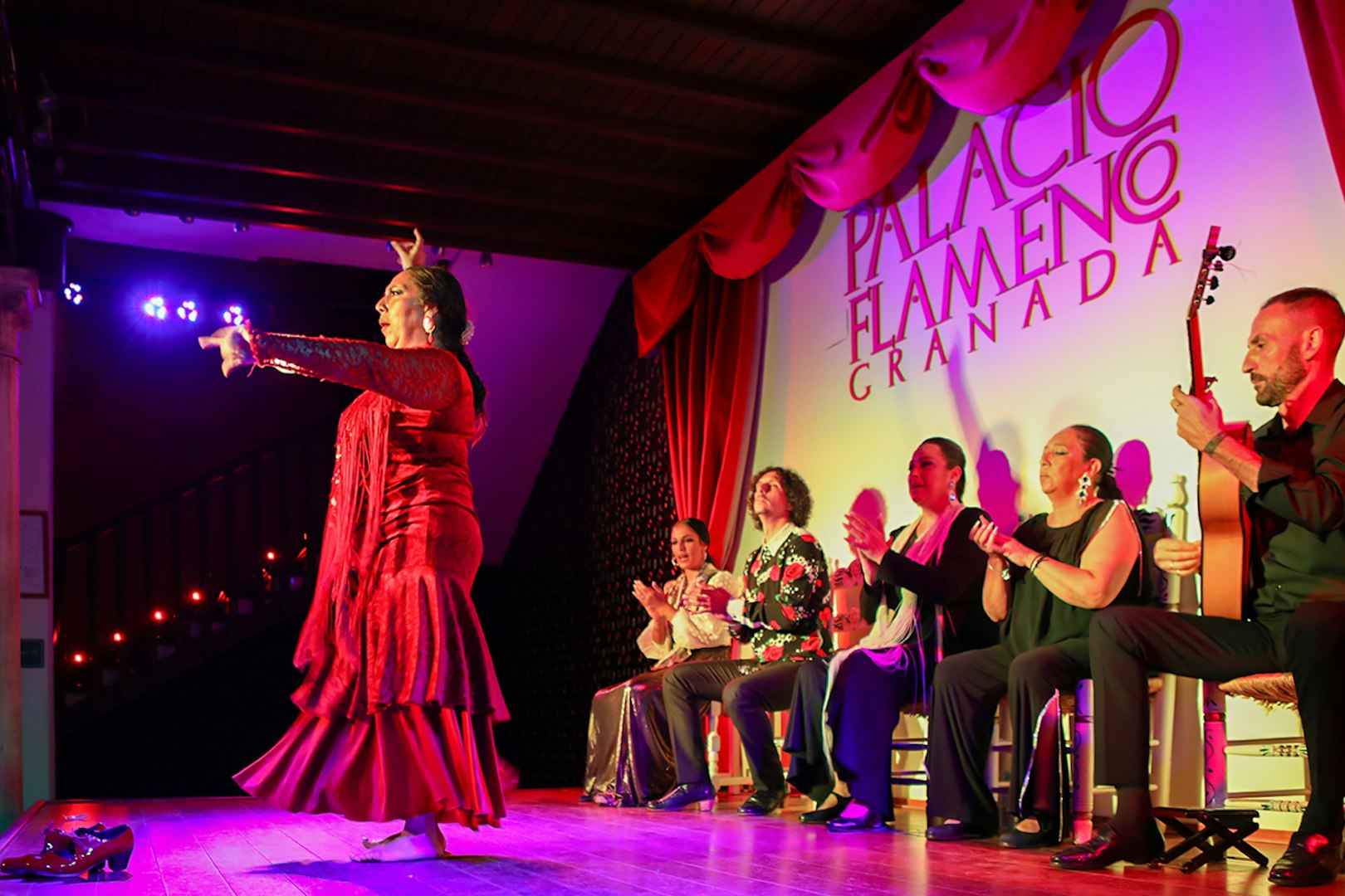 Flamenco dancer performing at Palacio de los Olvidados, Granada, with musicians and audience.