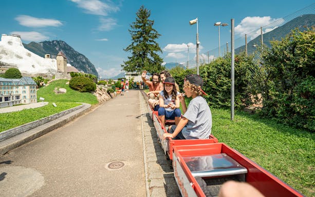 Visitors ride a miniature train at Swissminiatur park with model Swiss landmarks.