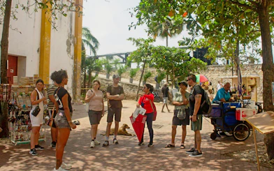 Tour group exploring Cartagena's Old City with a guide near street vendors.