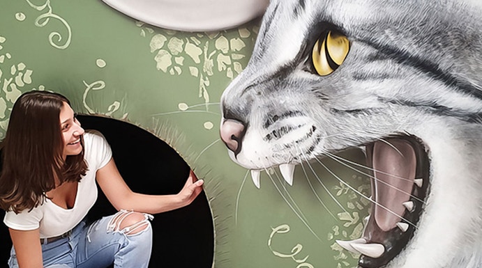 Woman interacting with giant cat illusion at Museum of Fantastic Illusions.