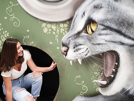 Woman interacting with giant cat illusion at Museum of Fantastic Illusions.