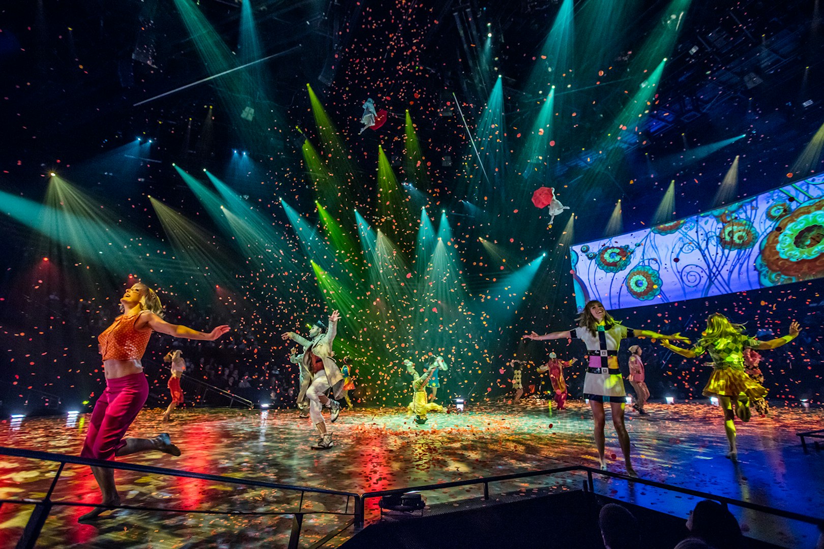 Performers on stage during The Beatles LOVE show with colorful lights and confetti.