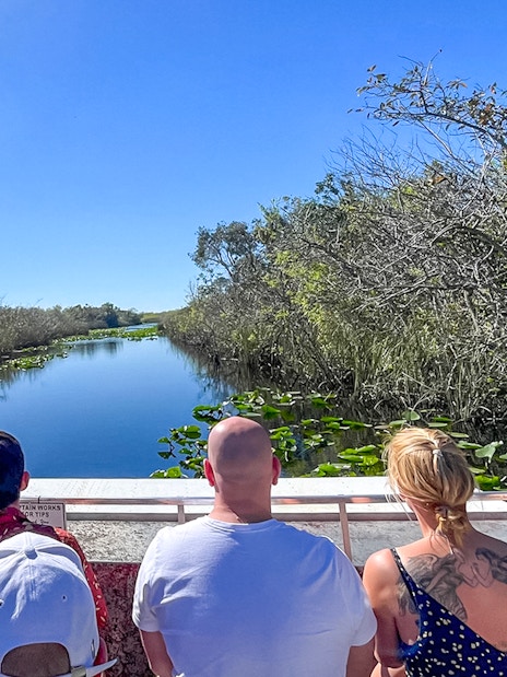 Tourists on an airboat in Everglades National Park, Miami, surrounded by water and vegetation.
