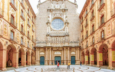 Montserrat Monastery courtyard with detailed facade and visitors exploring.