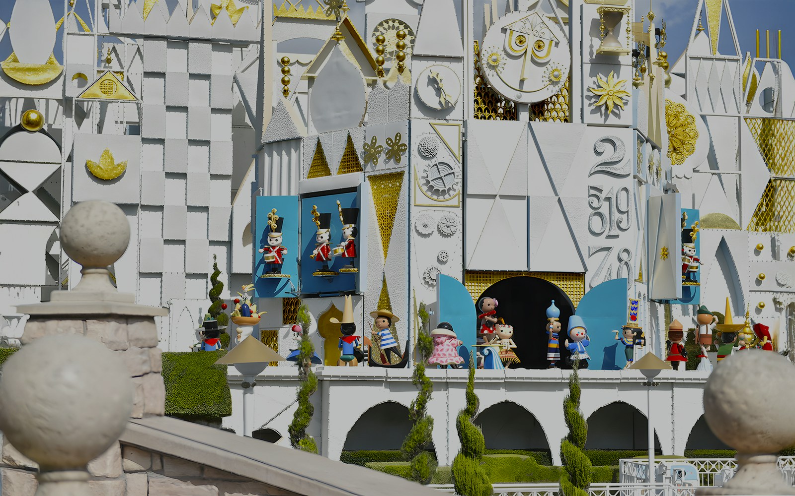 It's a Small World ride facade at Disneyland Park, California, featuring colorful figures and clock.
