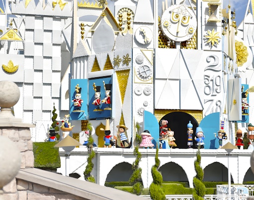 It's a Small World ride facade at Disneyland Park, California, featuring colorful figures and clock.