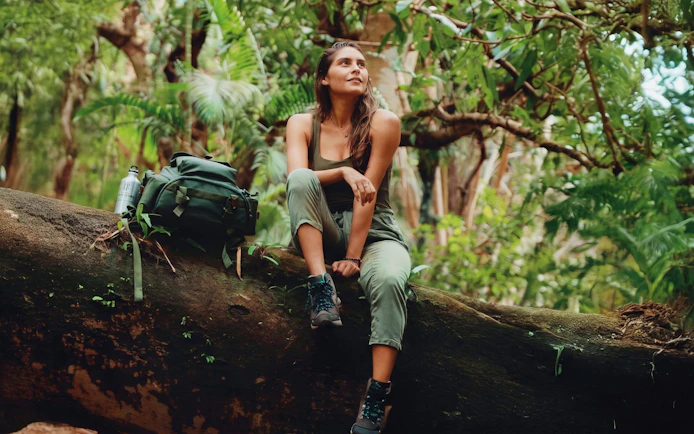 Woman sitting on a log in lush forest during Bel Ombre wilderness tour.