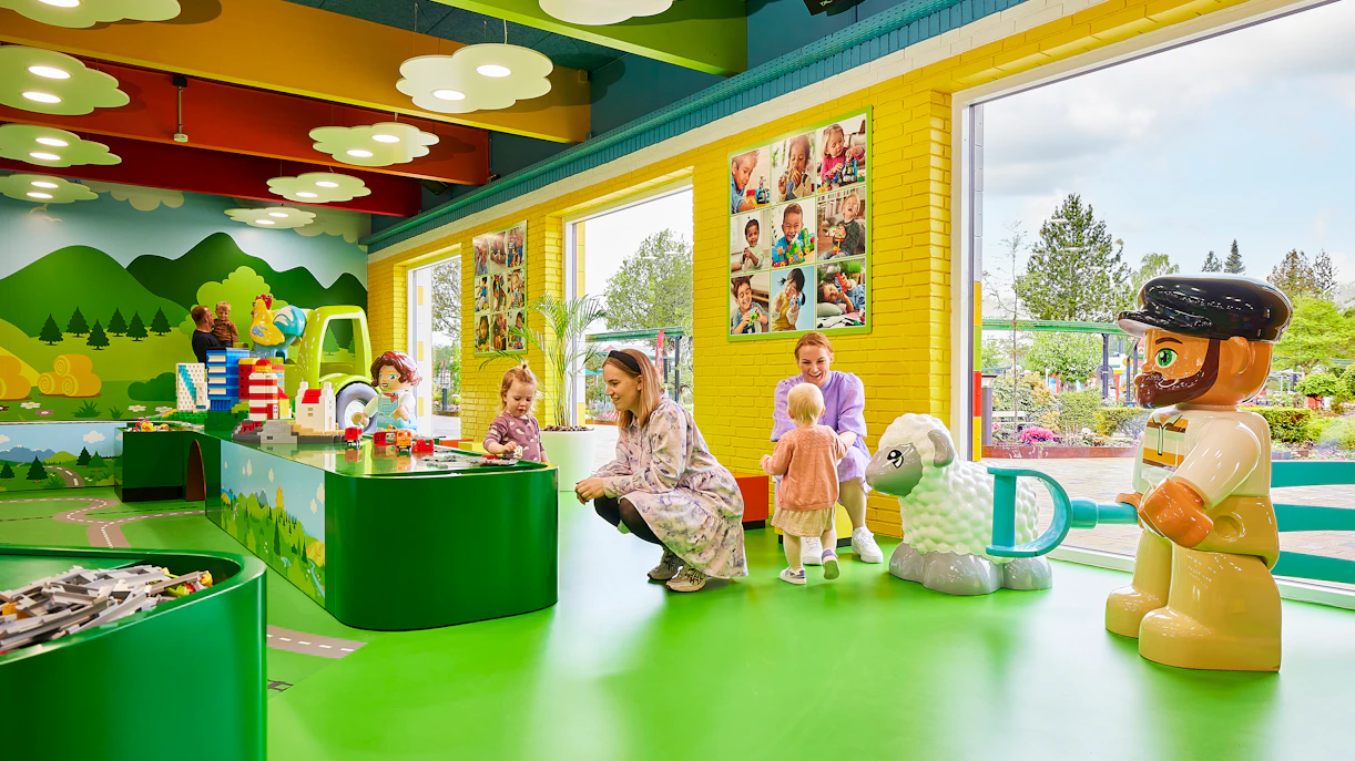 Children playing with LEGO bricks inside LEGOLAND Billund's colorful play area.