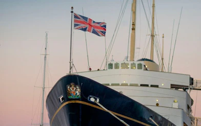 Royal Yacht Britannia with Union Jack flag at sunset.