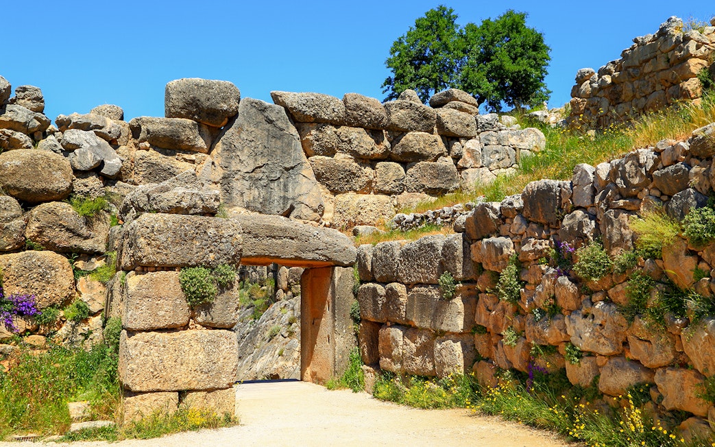 Mycenae archaeological site entrance with ancient stone walls and greenery.