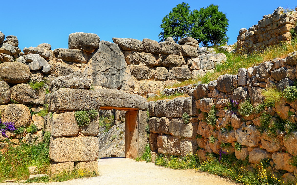 Mycenae archaeological site entrance with ancient stone walls and greenery.
