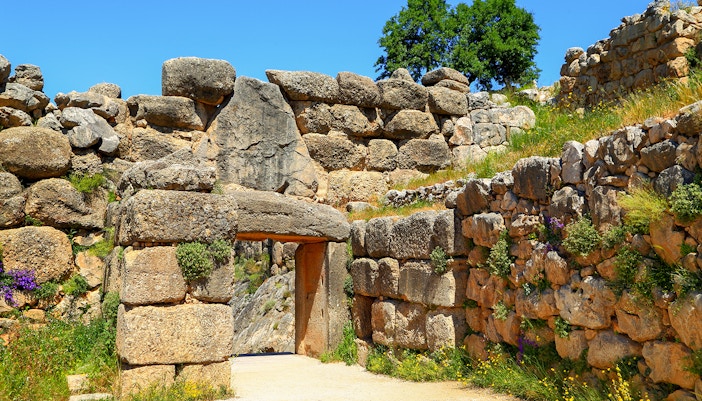 Mycenae archaeological site entrance with ancient stone walls and greenery.