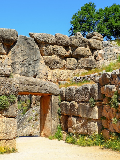 Mycenae archaeological site entrance with ancient stone walls and greenery.