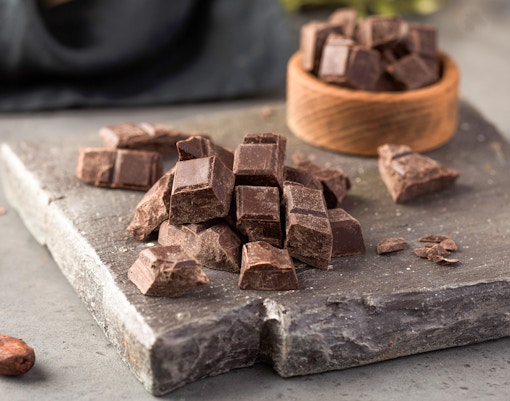Handcrafted chocolate bars displayed on a wooden table in a Parisian chocolatier shop.