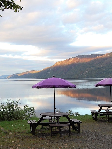 Picnic tables with purple umbrellas by Loch Ness near Fort Augustus.