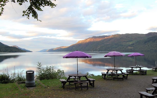 Picnic tables with purple umbrellas by Loch Ness near Fort Augustus.