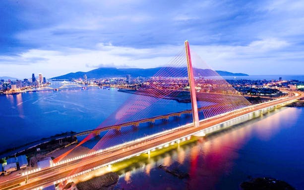 Da Nang skyline with illuminated bridge at dusk, viewed from Poseidon cruise.