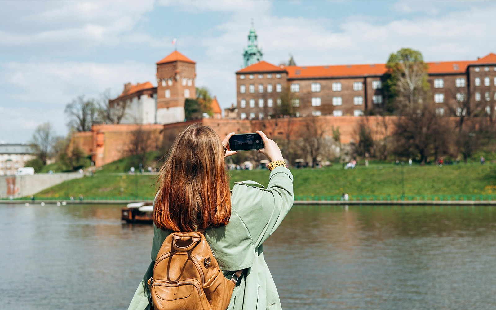 Tourist photographing Wawel Castle from across the Vistula River in Krakow.