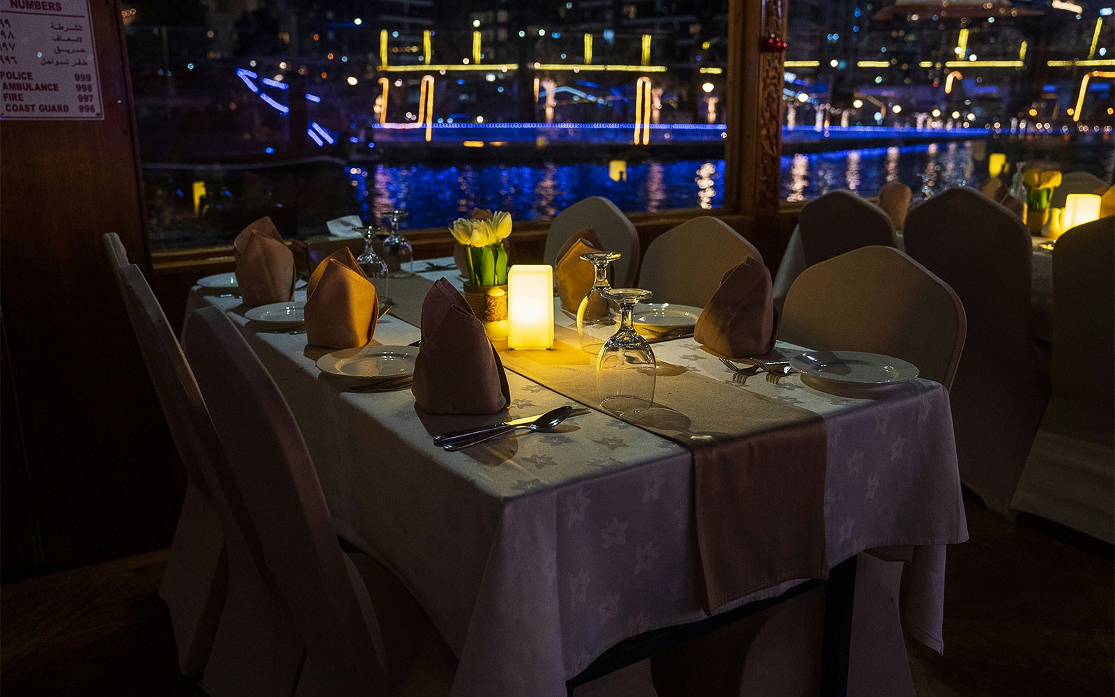 Dhow boat with guests enjoying dinner and live entertainment on Dubai Creek.