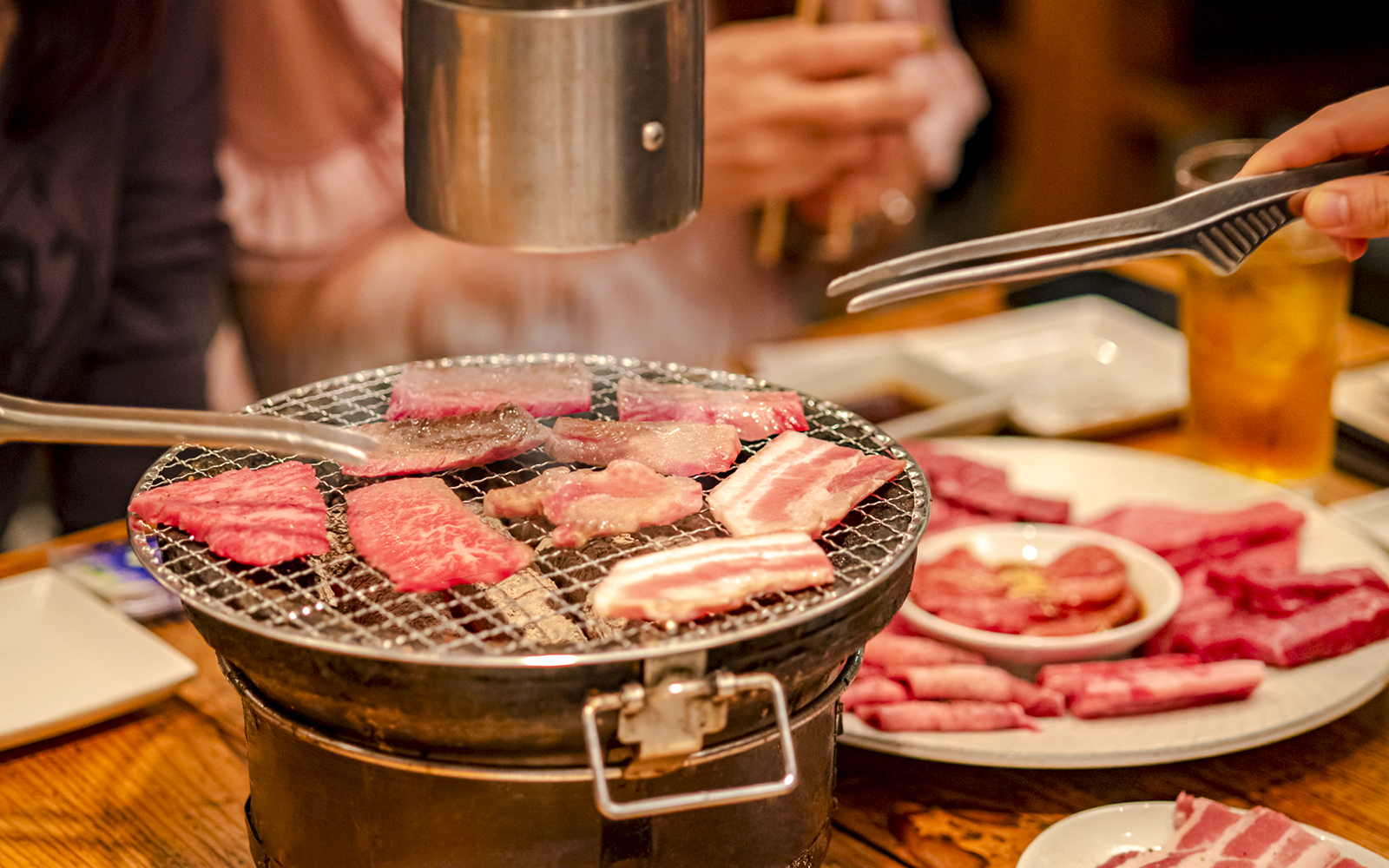 Grilling meat on a tabletop barbecue at a Japanese yakiniku restaurant.