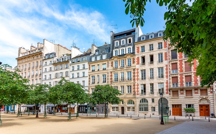 Historic buildings on Notre Dame Island, Paris, with trees lining a quiet square.