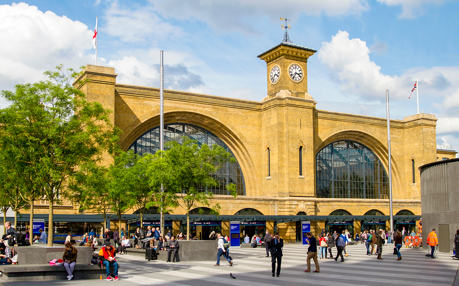 King's Cross Station facade with clock tower, London, bustling with people.