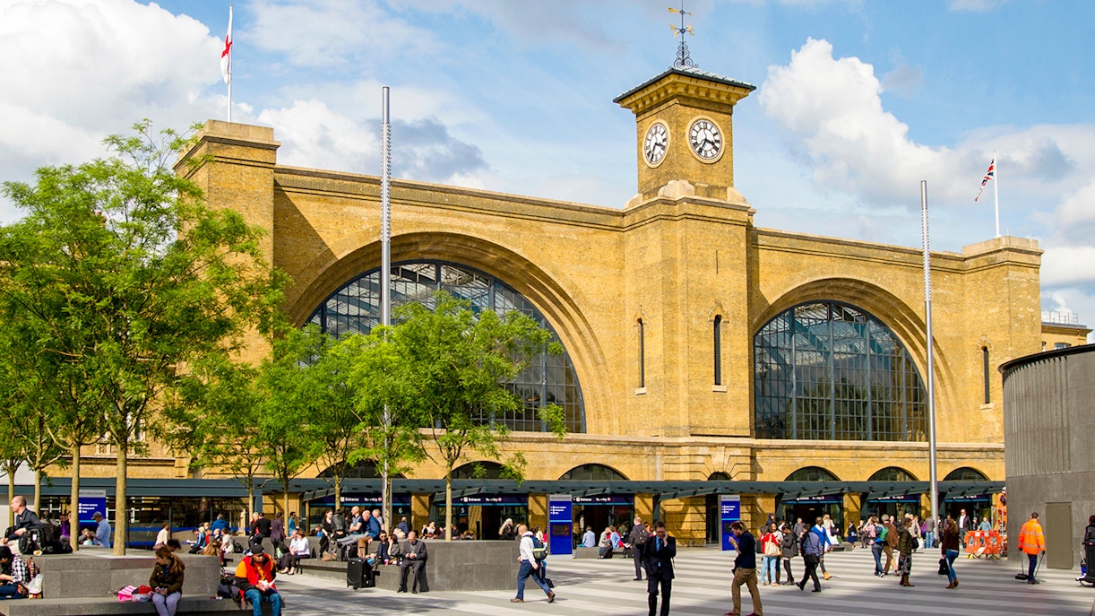 King's Cross Station facade with clock tower, London, bustling with people.
