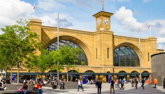 King's Cross Station facade with clock tower, London, bustling with people.
