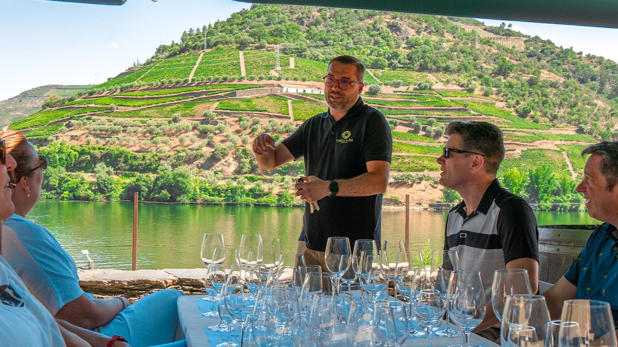 Tourists tasting wine with a guide overlooking the Douro Valley vineyards.