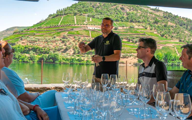 Tourists tasting wine with a guide overlooking the Douro Valley vineyards.