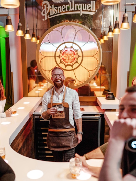 Tourists enjoying beer tasting at Pilsner Urquell Experience bar.