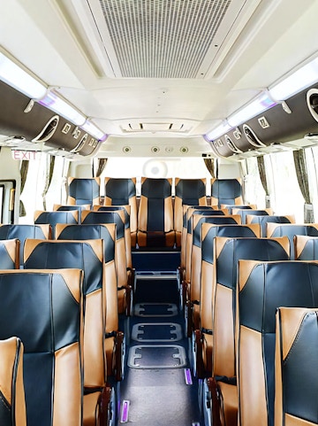 Interior of a tour bus with leather seats, used for transfers from Don Mueang International Airport.