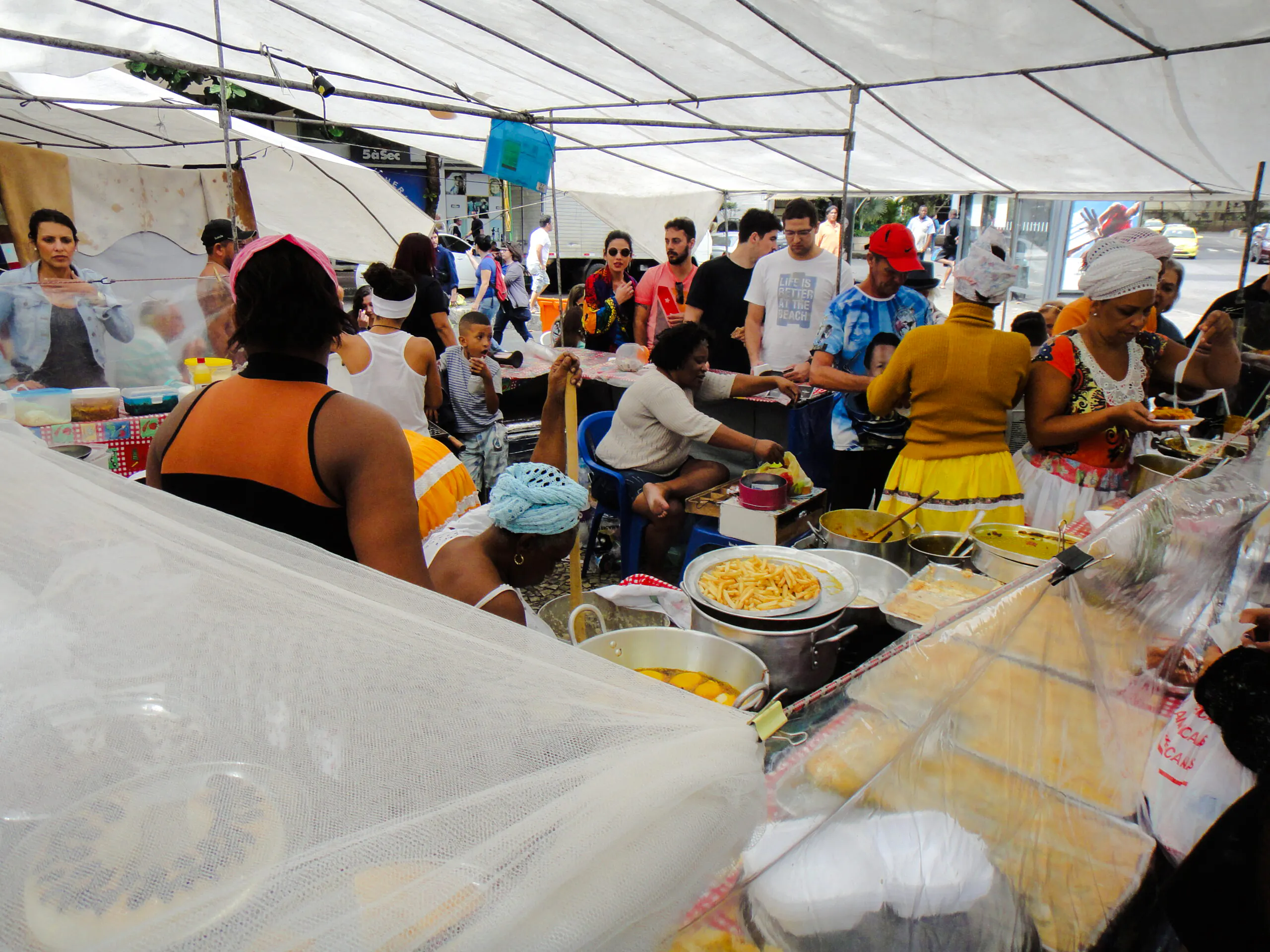 Visitors exploring food stalls at Ipanema Street Market with a local guide, Rio de Janeiro.