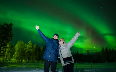 Couple enjoying Northern Lights in Rovaniemi, Finland.