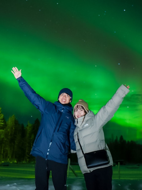 Couple enjoying Northern Lights in Rovaniemi, Finland.