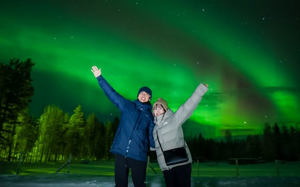 Couple enjoying Northern Lights in Rovaniemi, Finland.