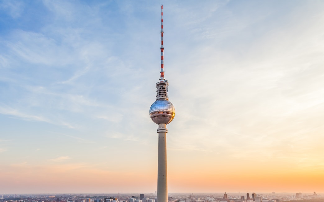 Berlin TV Tower at sunset with cityscape below.