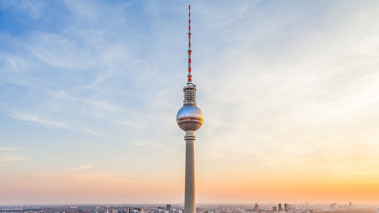 Berlin TV Tower at sunset with cityscape below.