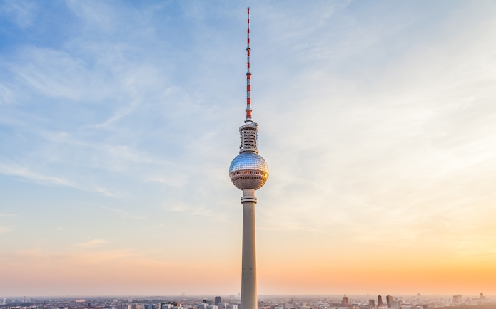 Berlin TV Tower at sunset with cityscape below.