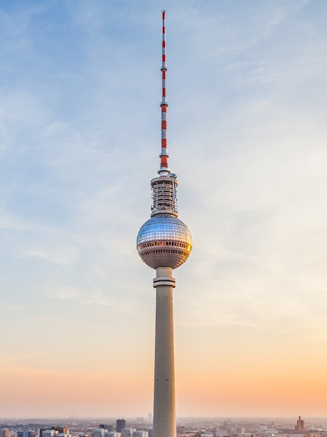 Berlin TV Tower at sunset with cityscape below.